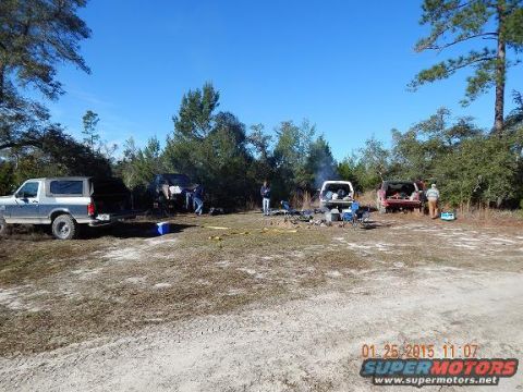 1989 Ford Bronco - Several vehicles are gathered at a campsite with a campfire and people milling about.