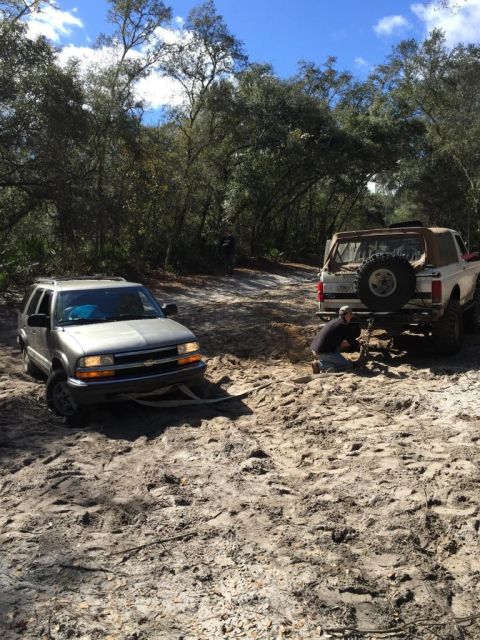 1989 Ford Bronco - A white 1989 Ford Bronco is being assisted by a silver SUV while stuck in the mud.