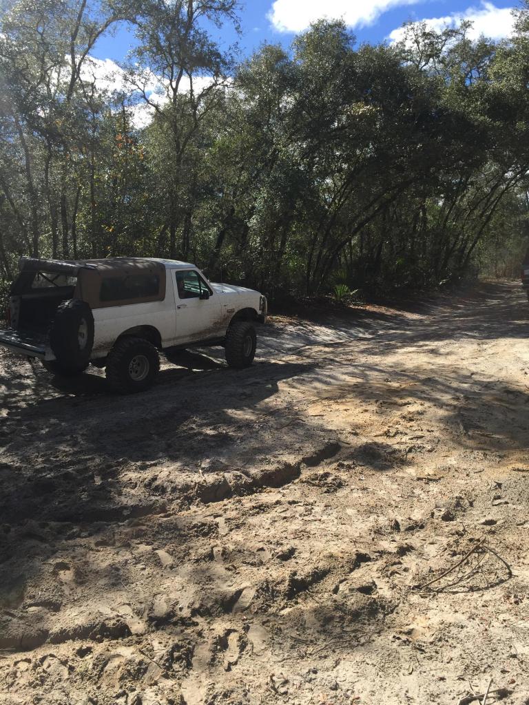 1989 Ford Bronco with aftermarket wheels and tires on a sandy trail