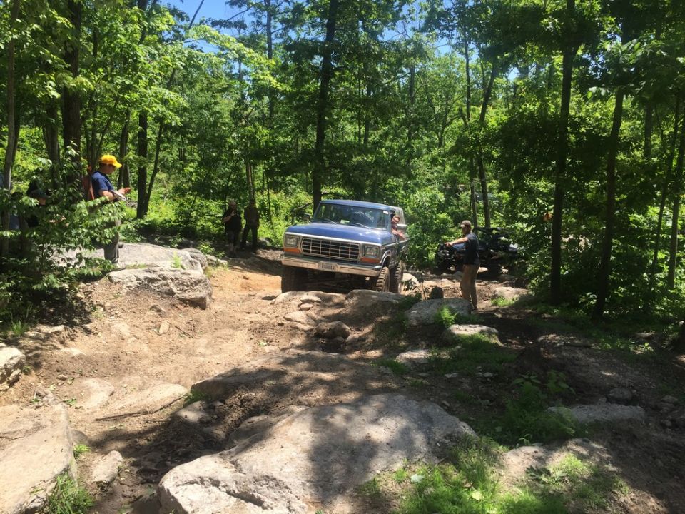 Blue SUV on rocky trail, second vehicle visible behind