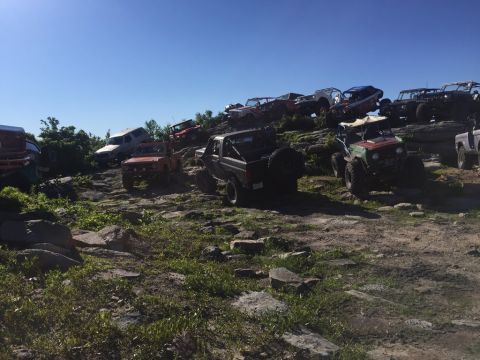 1989 Ford Bronco - Multiple off-road vehicles navigate a challenging rocky landscape on a sunny day.