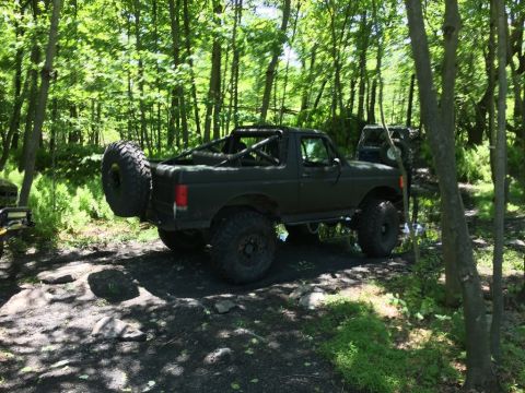 1989 Ford Bronco - Modified 1989 Ford Bronco navigating an off-road trail with another vehicle visible in the background.