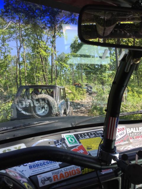 1989 Ford Bronco - Multiple off-road vehicles navigate a wooded trail on a sunny day. The view is from the perspective of one of the vehicles.