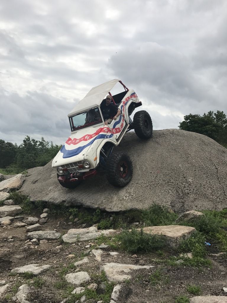 Ford Bronco climbing a large rock on an off-road trail