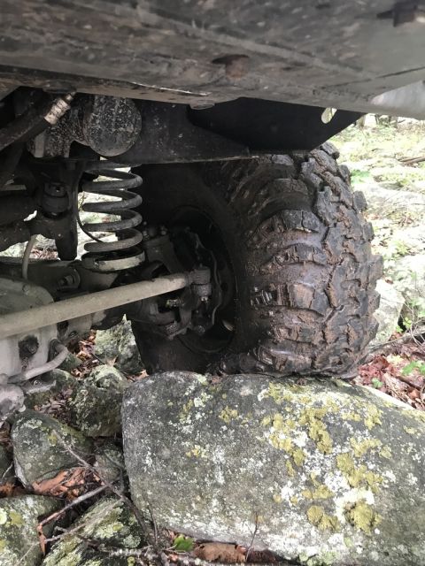 1989 Ford Bronco - Close-up view of an off-road vehicle's tire and suspension system navigating rocky terrain.