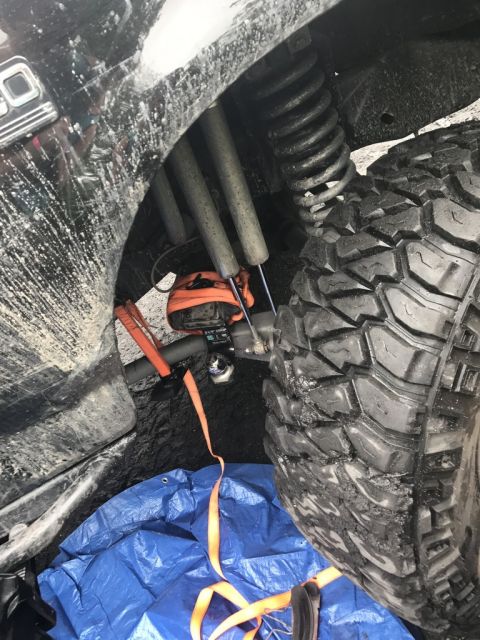 1989 Ford Bronco - Close-up of the rear suspension and tire on a 1989 Ford Bronco, showing modifications and tie-down straps.