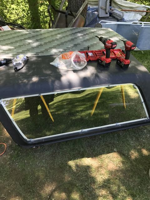 1989 Ford Bronco - A black hard top is laid out on the grass with tools and supplies on its surface.