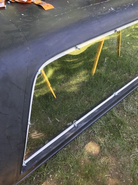 1989 Ford Bronco - Vehicle hard top with window frame, showing reflection of yellow supports on the ground.