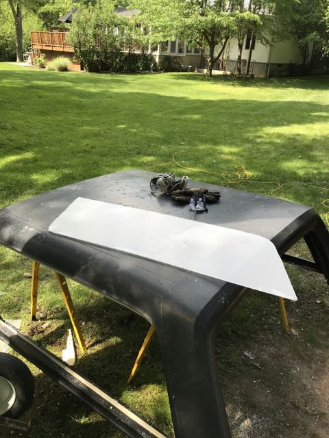 1989 Ford Bronco - A vehicle hardtop is placed on sawhorses outdoors, with a metal panel and tools on its surface.