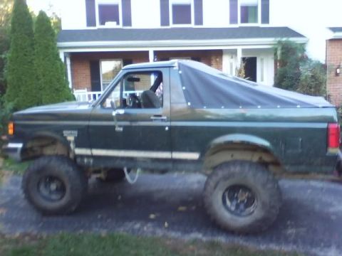 1989 Ford Bronco - This lifted Ford Bronco features a dark soft top covering the rear.