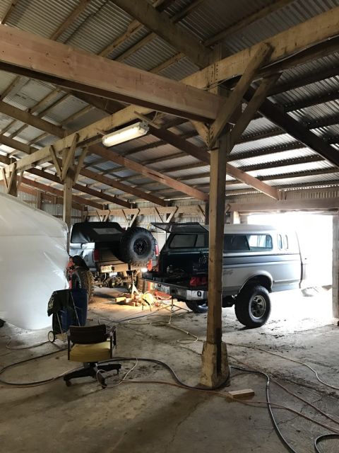 1989 Ford Bronco - Two 1989 Ford Broncos are visible in a garage, with one lifted for service.