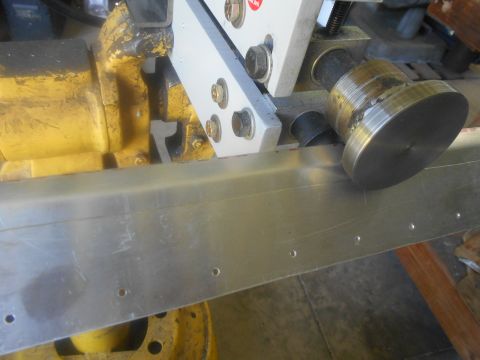 1992 Ford Bronco - Close-up view of metal fabrication equipment in action, with a roller shaping a metal sheet.