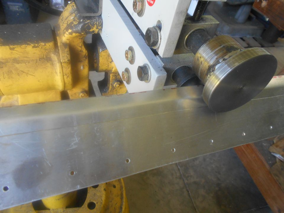 Metal fabrication equipment with a roller pressing on a metal sheet