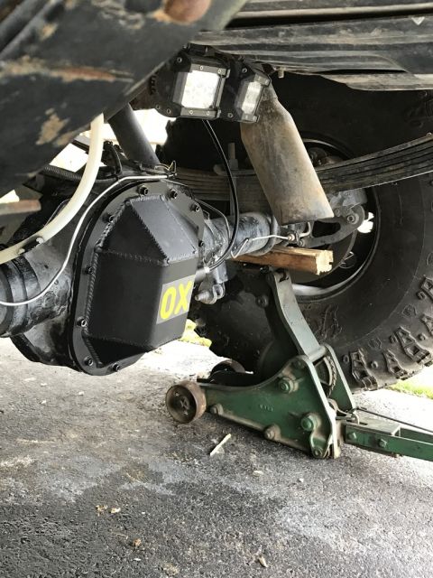 1989 Ford Bronco - Close-up of a vehicle's rear axle an OX locker and auxiliary lights, supported by a jack.