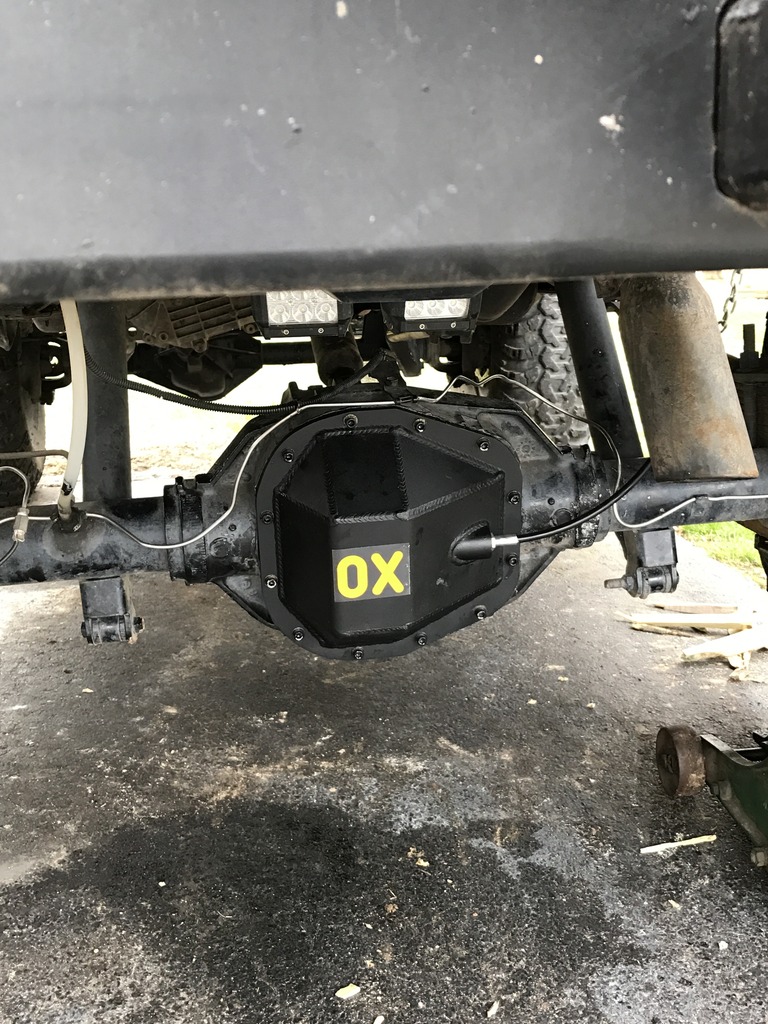 Rear differential cover with yellow OX logo. Part of a vehicle's drivetrain