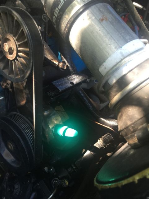 1989 Ford Bronco - Close-up view of an engine bay, highlighting a lit green indicator light and various engine components.