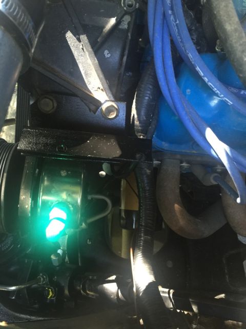 1989 Ford Bronco - Close-up of an engine bay showing various components and a bright green light.
