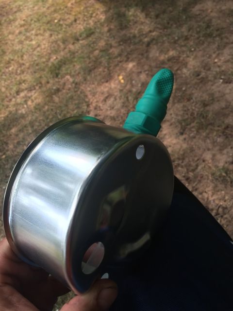 1989 Ford Bronco - A gauge with a green fitting is held in a hand, with grass in the background.