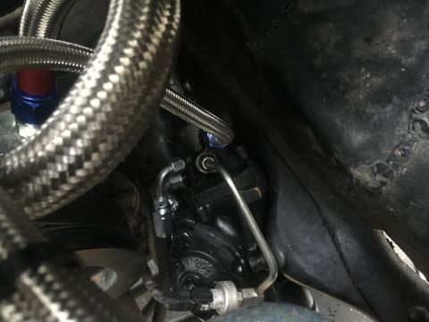 1989 Ford Bronco - Close-up of a power steering pump with braided hoses and metal lines, part of a vehicle's steering system.