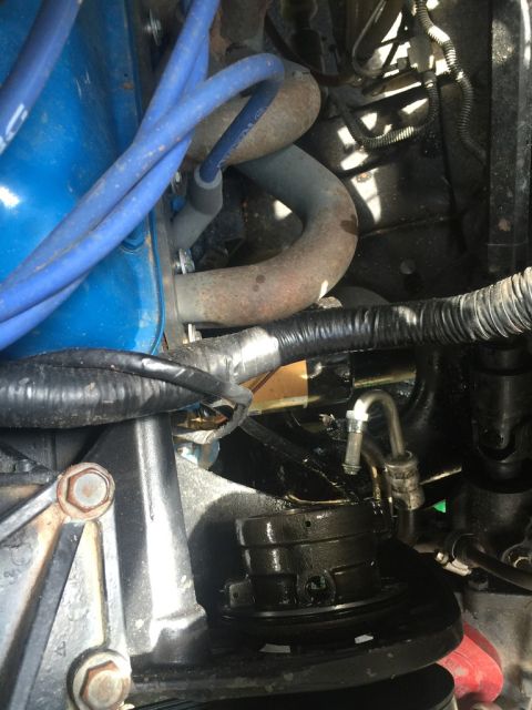 1989 Ford Bronco - Close-up view of engine components, including spark plug wires and exhaust piping.