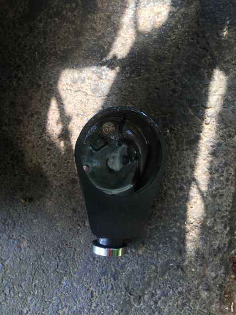 1989 Ford Bronco - Close-up of a steering column part, possibly from a Ford Bronco, on a rough surface.