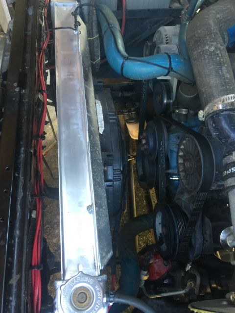 1989 Ford Bronco - A close-up view of the engine bay of a vehicle, focusing on the radiator and various engine components. The radiator is a shiny aluminum un…