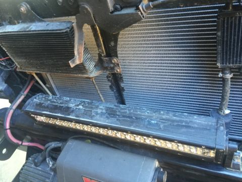 1989 Ford Bronco - A close-up view shows the front of a vehicle with a large radiator, an auxiliary cooler mounted above it, and a light bar below. Various ho…