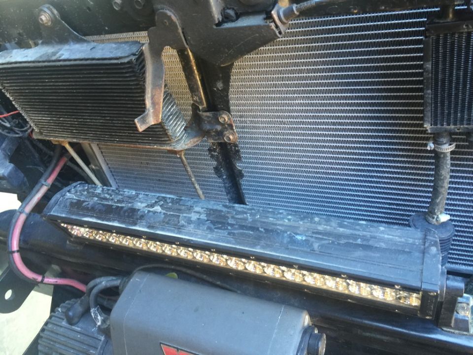 Vehicle radiator, auxiliary cooler, light bar, hoses, wiring, and winch motor.