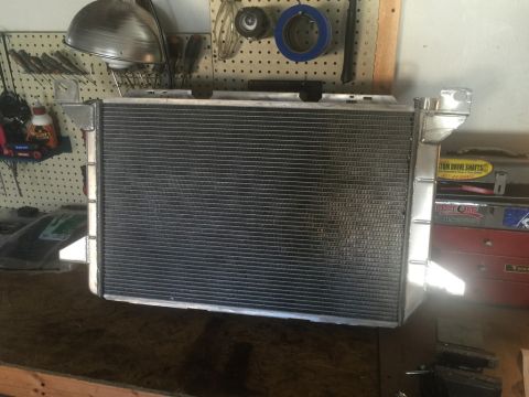 1989 Ford Bronco - A new aluminum radiator is shown mounted on a workbench in a garage setting. The radiator has a silver frame and a black finned core, with…