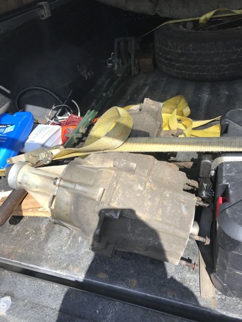 1989 Ford Bronco - A transfer case is shown lying in the bed of a pickup truck, secured with yellow ratchet straps. Other items visible include a spare tire,…