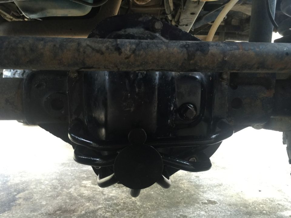 Underside of a vehicle showing a black differential housing and spring.