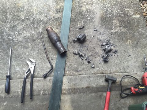 1989 Ford Bronco - A collection of tools and exhaust pipe parts are laid out on a concrete surface, possibly for a vehicle repair or modification project.