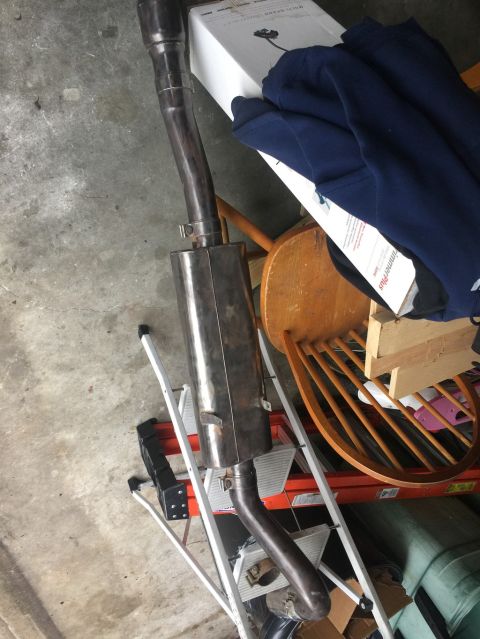 1989 Ford Bronco - Section of stainless steel exhaust pipe with a round muffler propped against a stool and ladder in a garage.