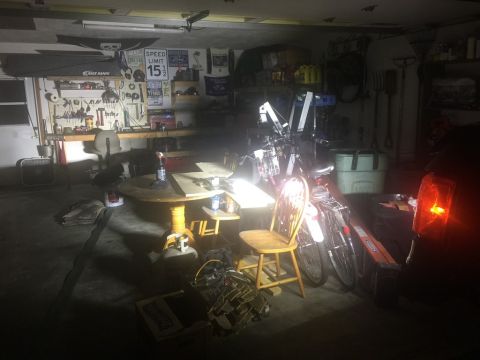 1989 Ford Bronco - This is a cluttered garage scene with tools, bicycles, and storage bins. A workbench is visible on the left with various tools mounted on t…