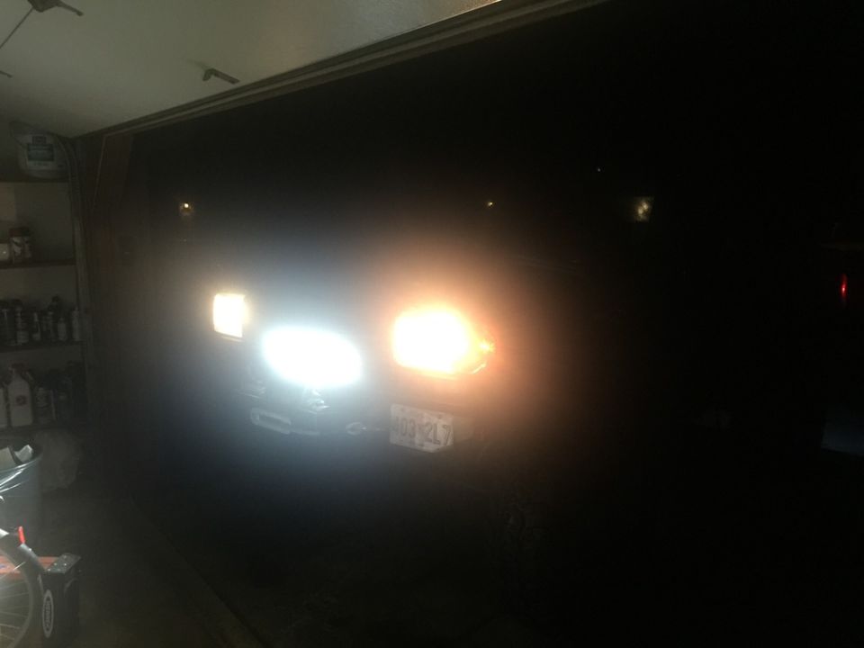 Front view of a vehicle in a garage with headlights on.