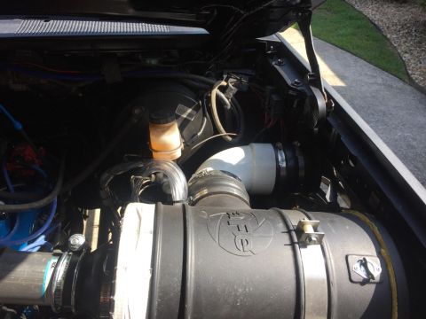 1989 Ford Bronco - The engine bay of a 1989 Ford Bronco shows a custom cold air intake system with a large black air filter housing and a white intake tube. V…