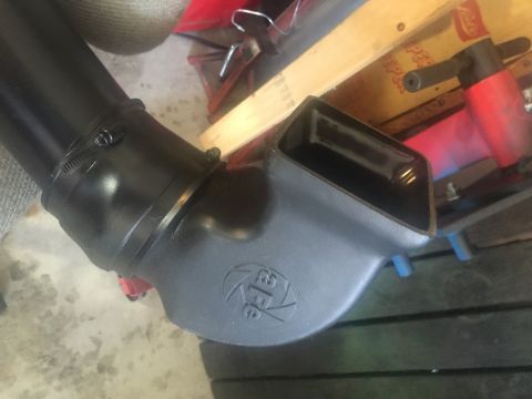 1989 Ford Bronco - A black plastic intake tube with a clamp is connected to a black air intake box with the AFE logo visible. The part is resting on a concret…
