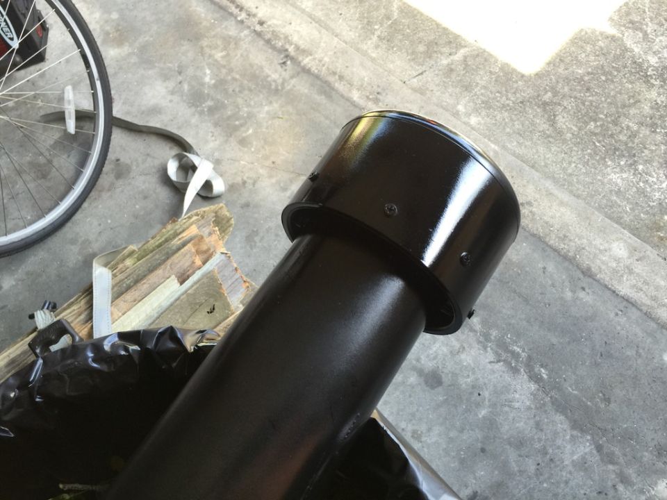 black snorkel pipe with screws, next to wood scraps and a bicycle wheel