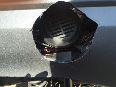 1989 Ford Bronco - A hole cut into the vehicle's bodywork exposes internal components and a black grille.