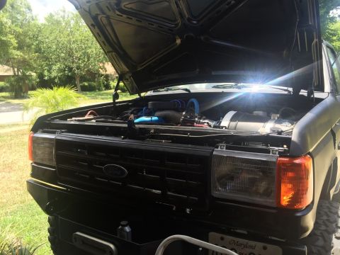 1989 Ford Bronco - Front view of a 1989 Ford Bronco, hood up, revealing the engine bay and grille.