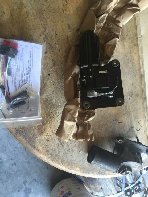 1989 Ford Bronco - A remanufactured windshield wiper motor assembly is shown on a wooden table next to its packaging and instructions. The part is black and a…