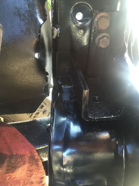 1989 Ford Bronco - A close-up view shows black painted metal components of a vehicle's frame or chassis, possibly near a door hinge area. Two rusty bolts secu…