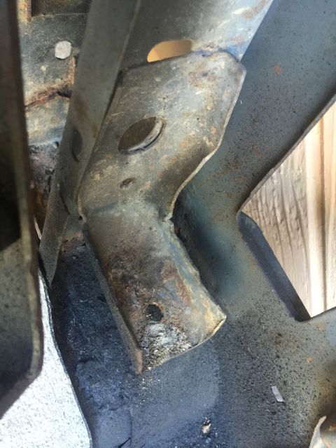 1989 Ford Bronco - This close-up shot shows a heavily rusted metal bracket attached to what appears to be a vehicle frame. The bracket has several holes and s…