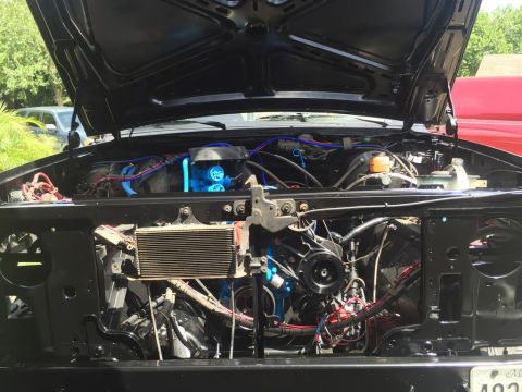 1989 Ford Bronco - The open hood of a black Ford Bronco reveals a detailed view of the engine bay, showcasing various engine components and wiring.