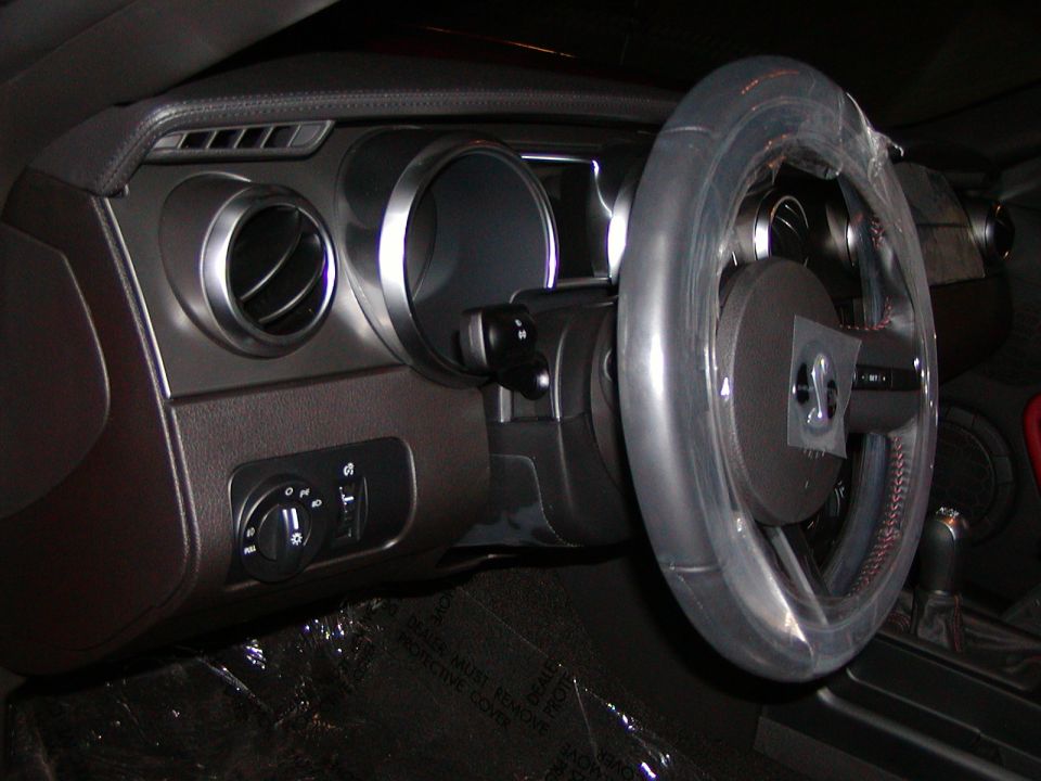 Interior of a car showing dashboard, steering wheel with plastic cover, and air vents.