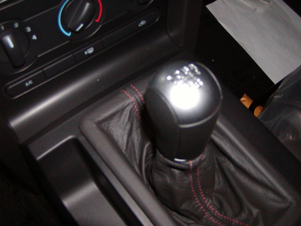 Interior of a car showing a 5-speed manual shift knob and center console.
