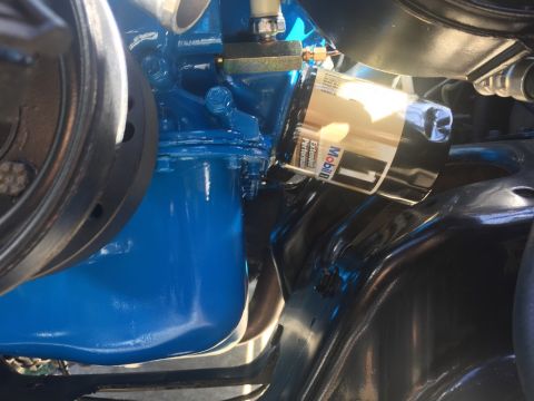 1989 Ford Bronco - A close-up view of a blue painted engine block with a Mobil 1 oil filter attached. The image shows part of a pulley system on the left.