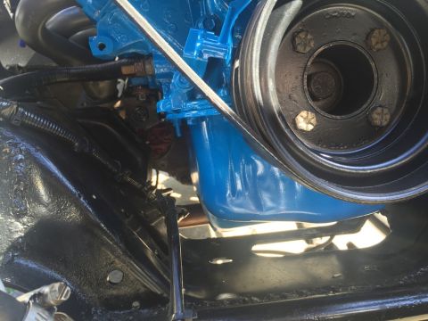 1989 Ford Bronco - A close-up view of a blue engine block and a black pulley system on a vehicle. The engine components are shiny and appear to be recently pa…