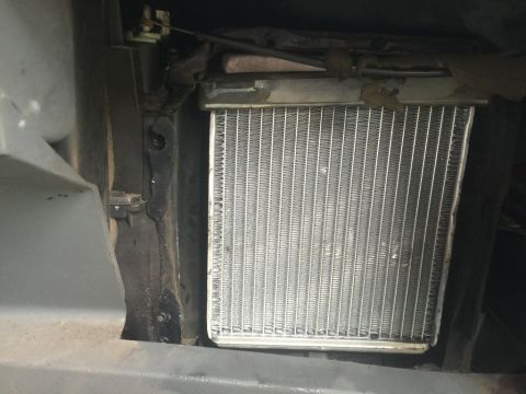 1989 Ford Bronco - A close-up view of a vehicle's heater core, showing its metallic fins and surrounding mounting hardware. The surrounding area appears to be…