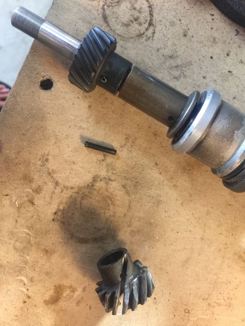 1989 Ford Bronco - A disassembled metal gear assembly with a broken pin and a separate gear piece resting on a wooden surface.